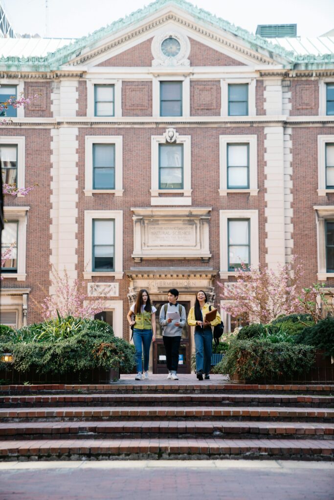 A diverse group of students walking on a university campus in spring.